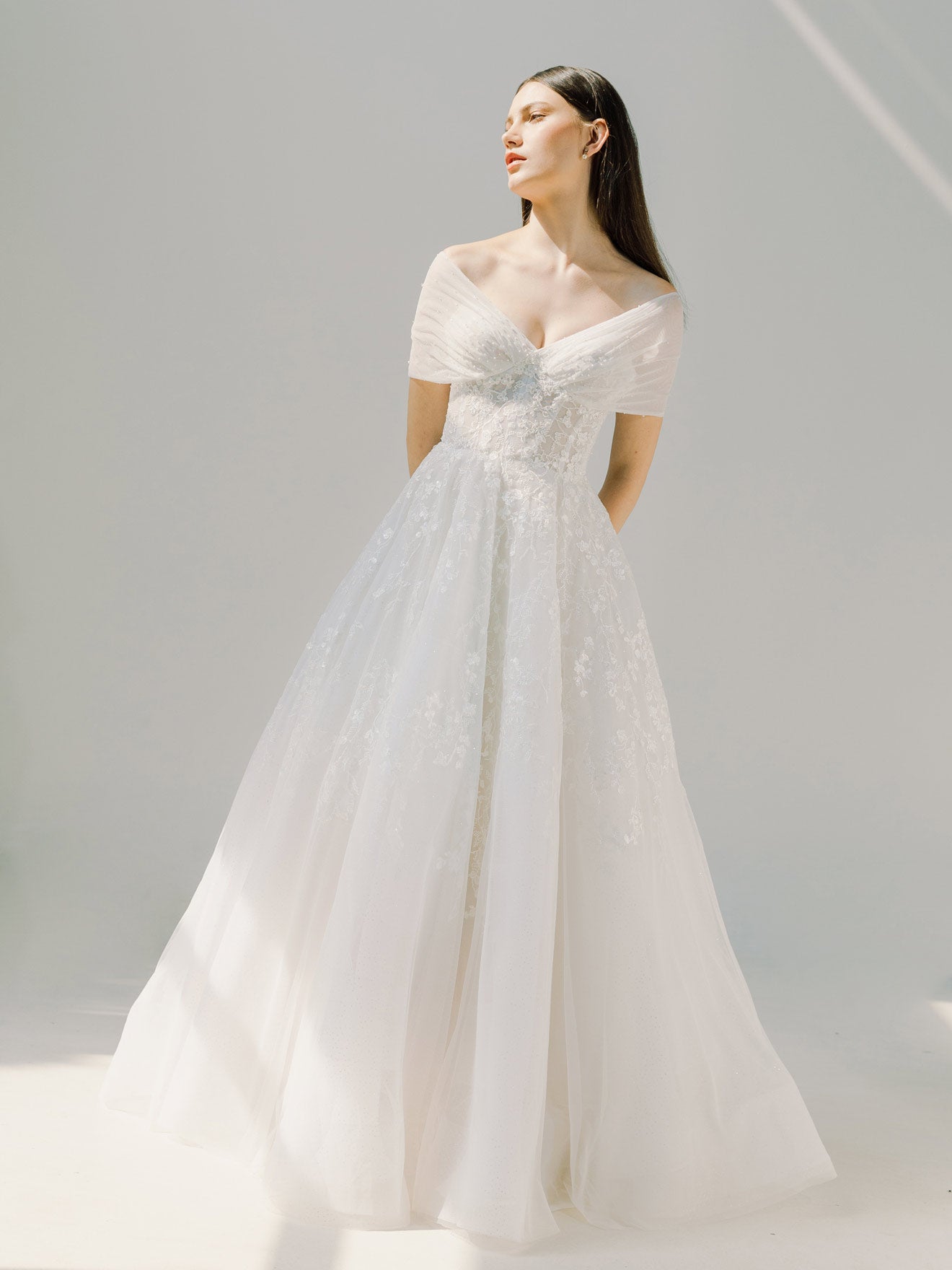 Woman wearing a white wedding dress against a plain background