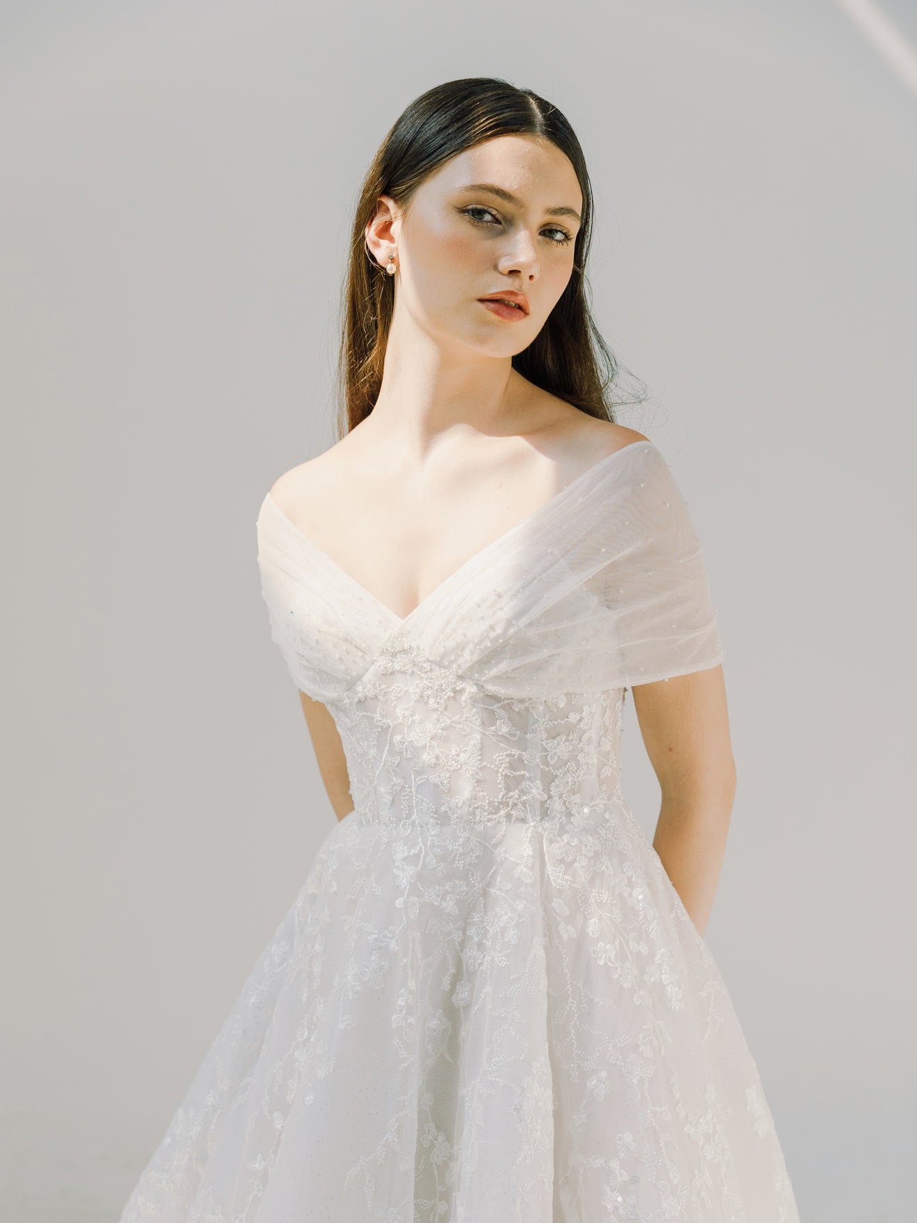 Woman wearing a white lace dress against a plain background