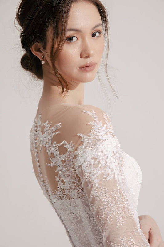 Woman wearing a lace wedding dress with a plain background