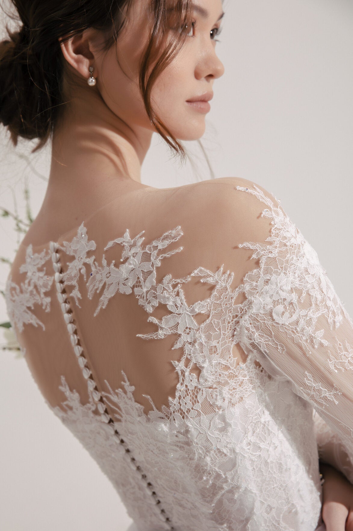Close-up of a person wearing a lace wedding dress with a blurred background