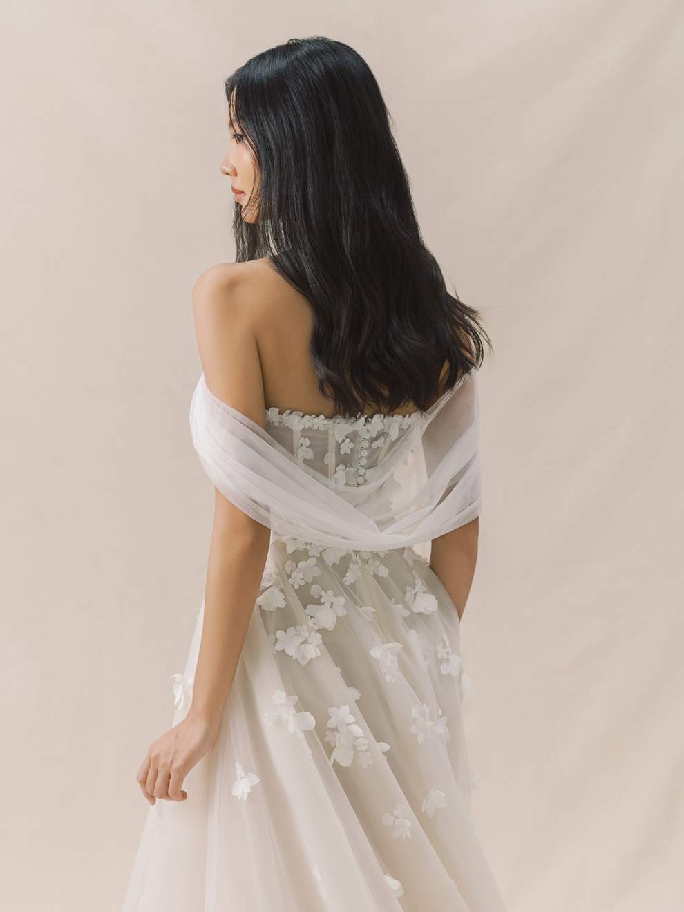 Woman wearing a floral off-shoulder dress against a beige background