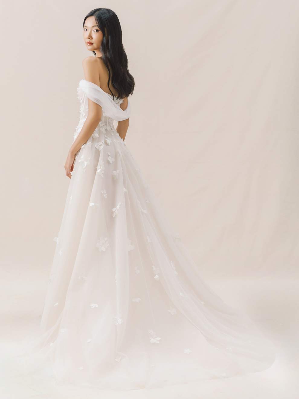 Woman wearing a white wedding dress against a plain background