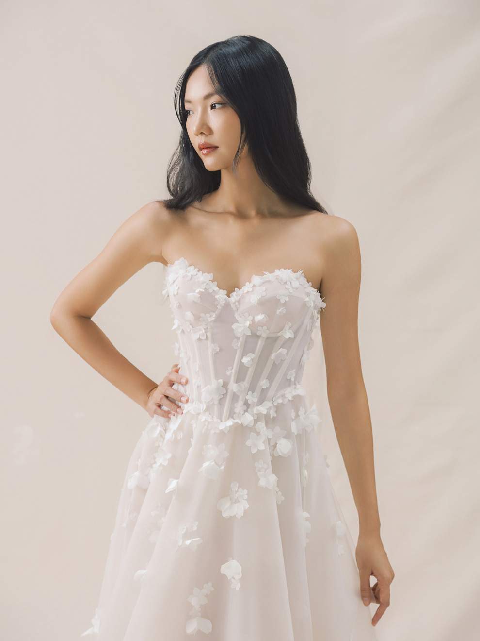 Woman wearing a strapless white floral dress against a plain background