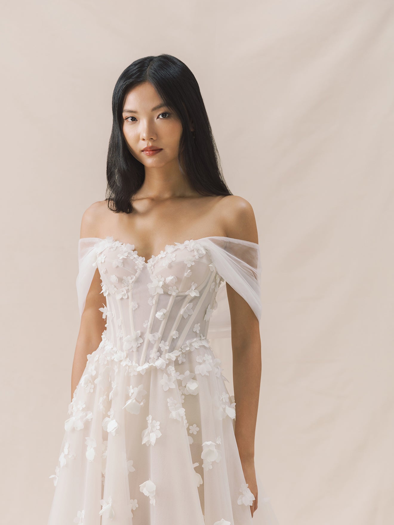 Woman wearing a white floral dress against a beige background