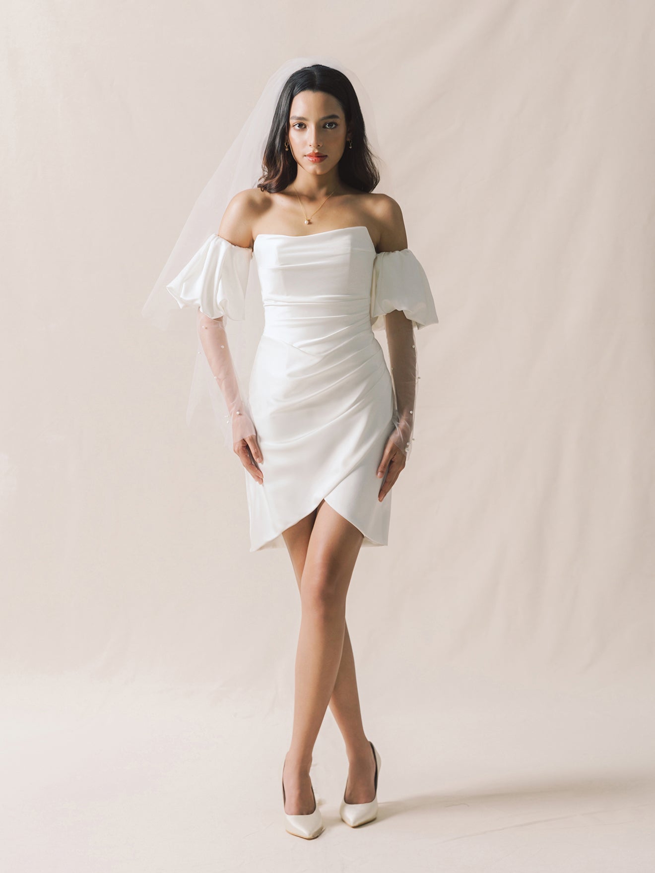 Woman wearing a white off-shoulder dress against a plain background