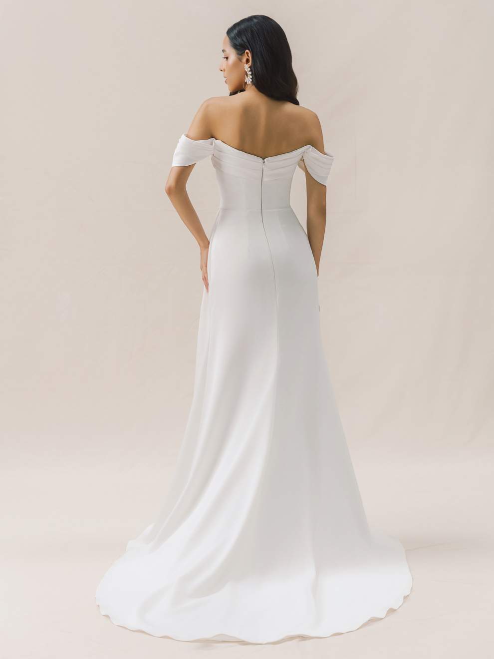 Woman wearing a white off-shoulder wedding dress on a beige background