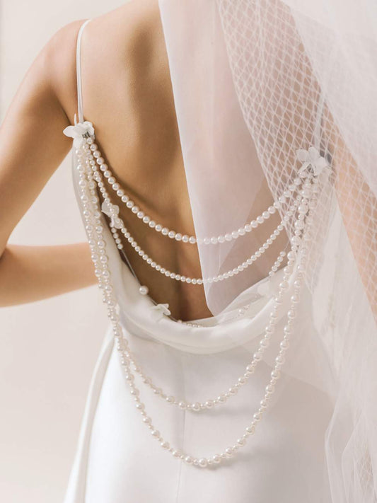 Pearl necklace draped over a white dress with a soft background