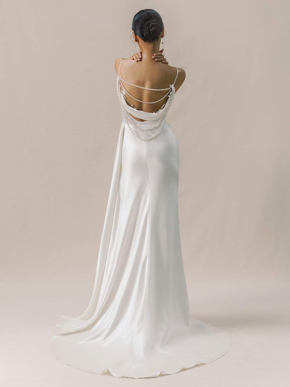 Woman wearing a white wedding dress with a long train on a plain background