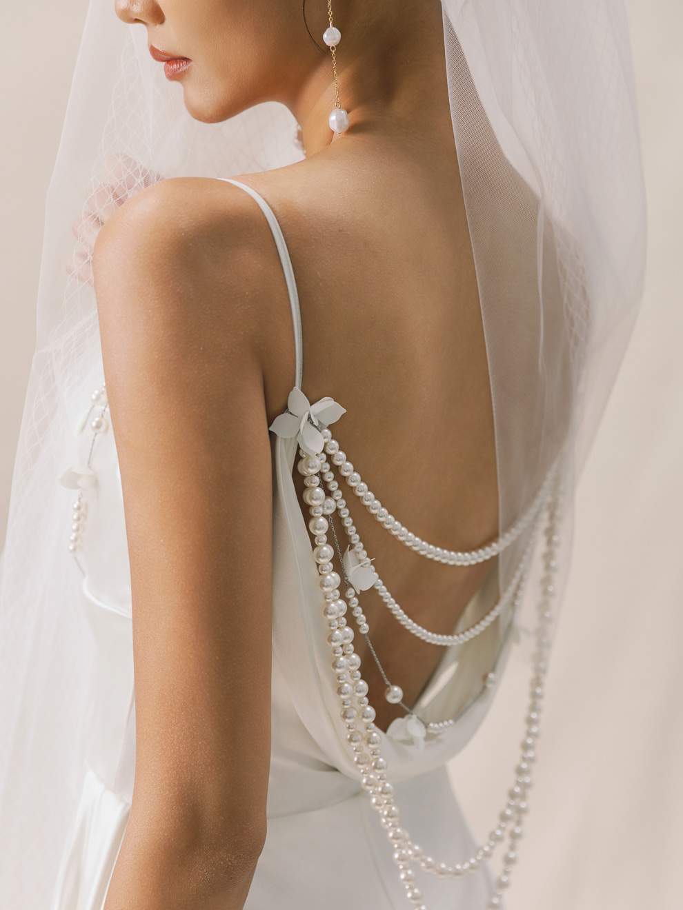 Close-up of a bride wearing a white dress with pearl detailing and a veil.