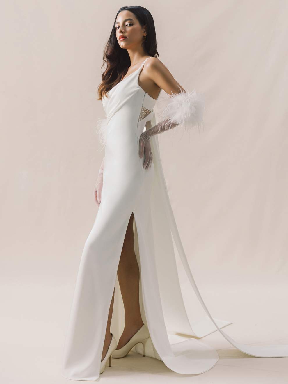 Woman in a white gown with a high slit on a plain background