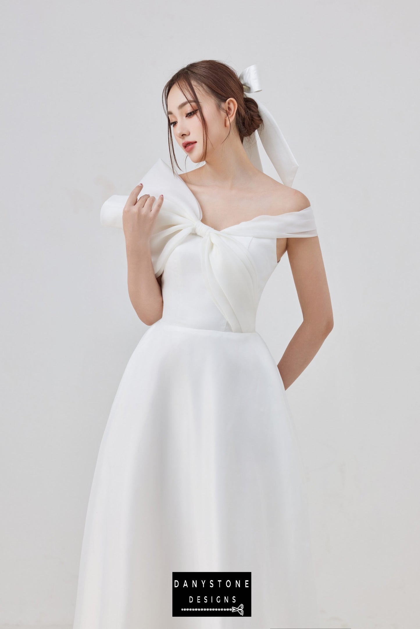 Elegant off-shoulder wedding dress with large bow detail and flowing skirt