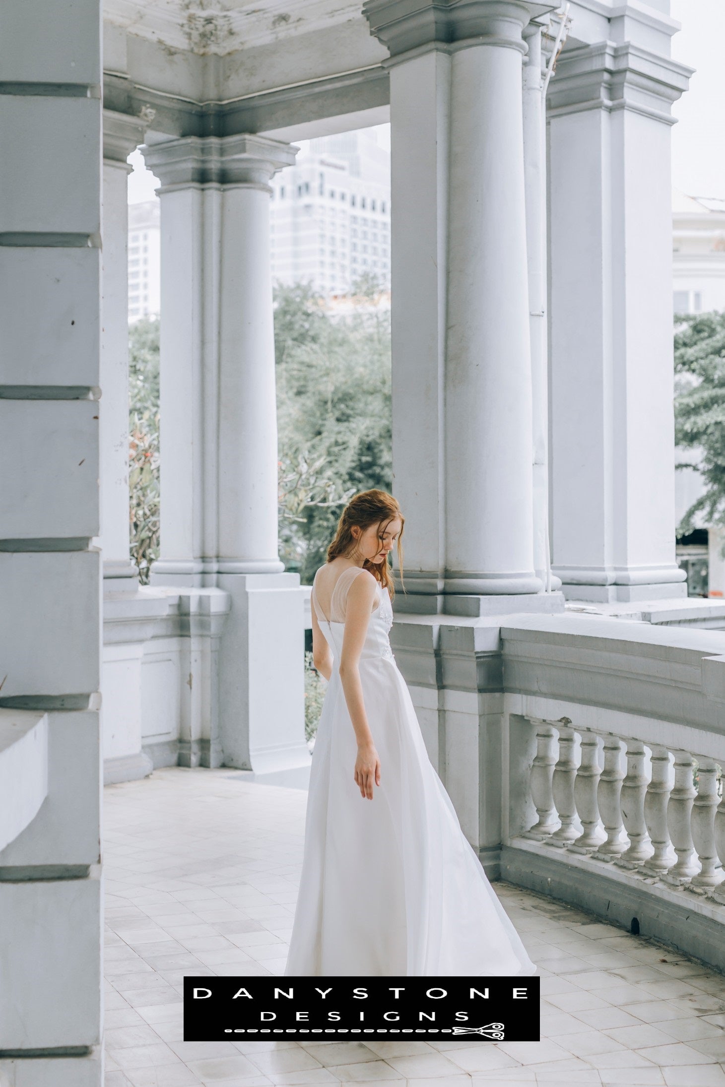 Bride wearing an elegant pleated chest wedding dress, standing on a classic balcony