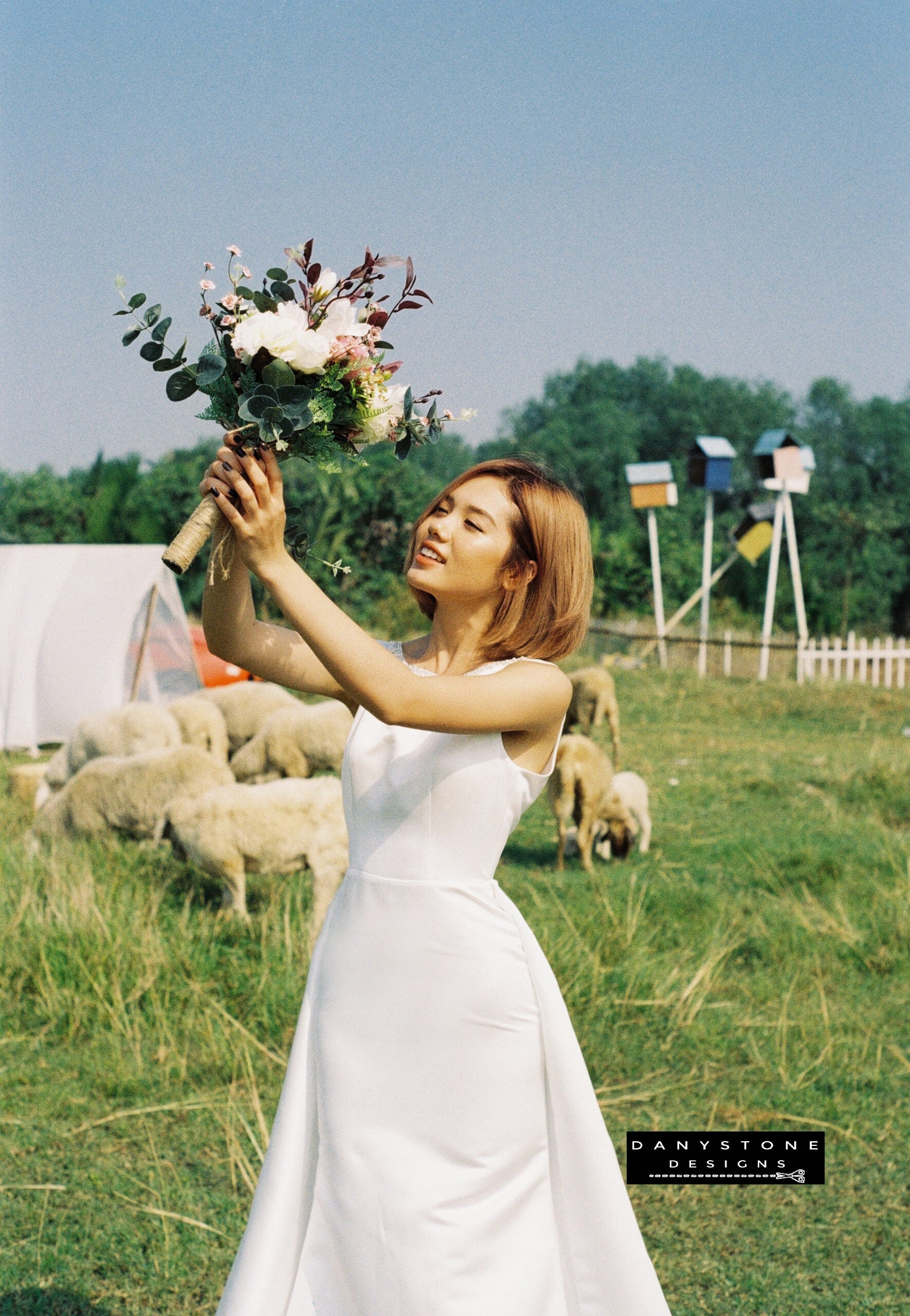 Side view of bride in a V-Back Wedding Dress with Long Fishtail holding a bouquet aloft