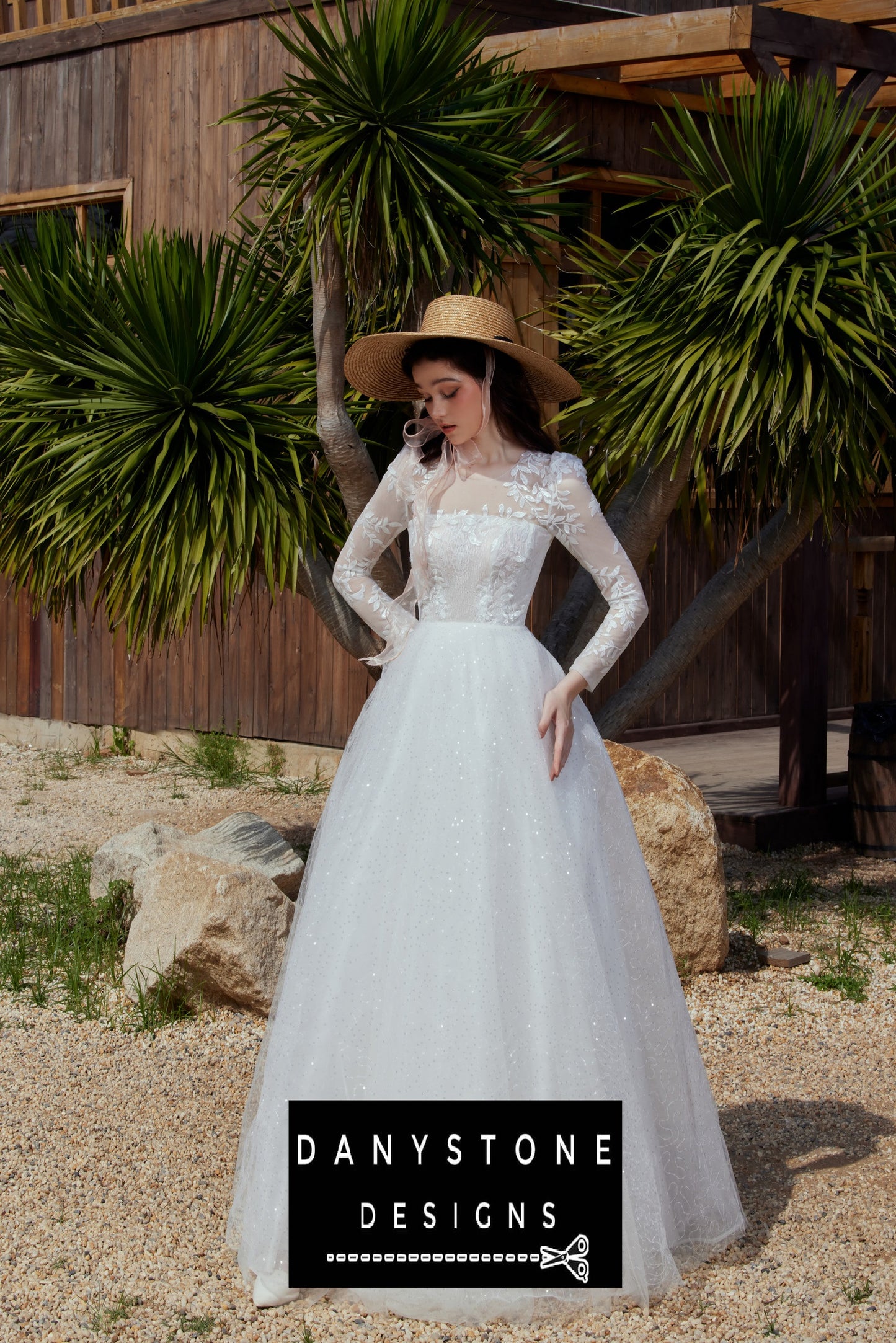 Bride in a Cinderella puffy wedding dress with a floral hat, standing in a garden with palm trees.