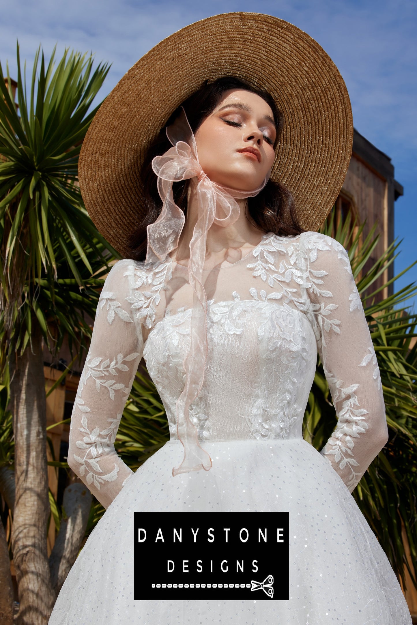 Close-up of the bride in a Cinderella puffy wedding dress with leaf motifs and a large hat, looking up.