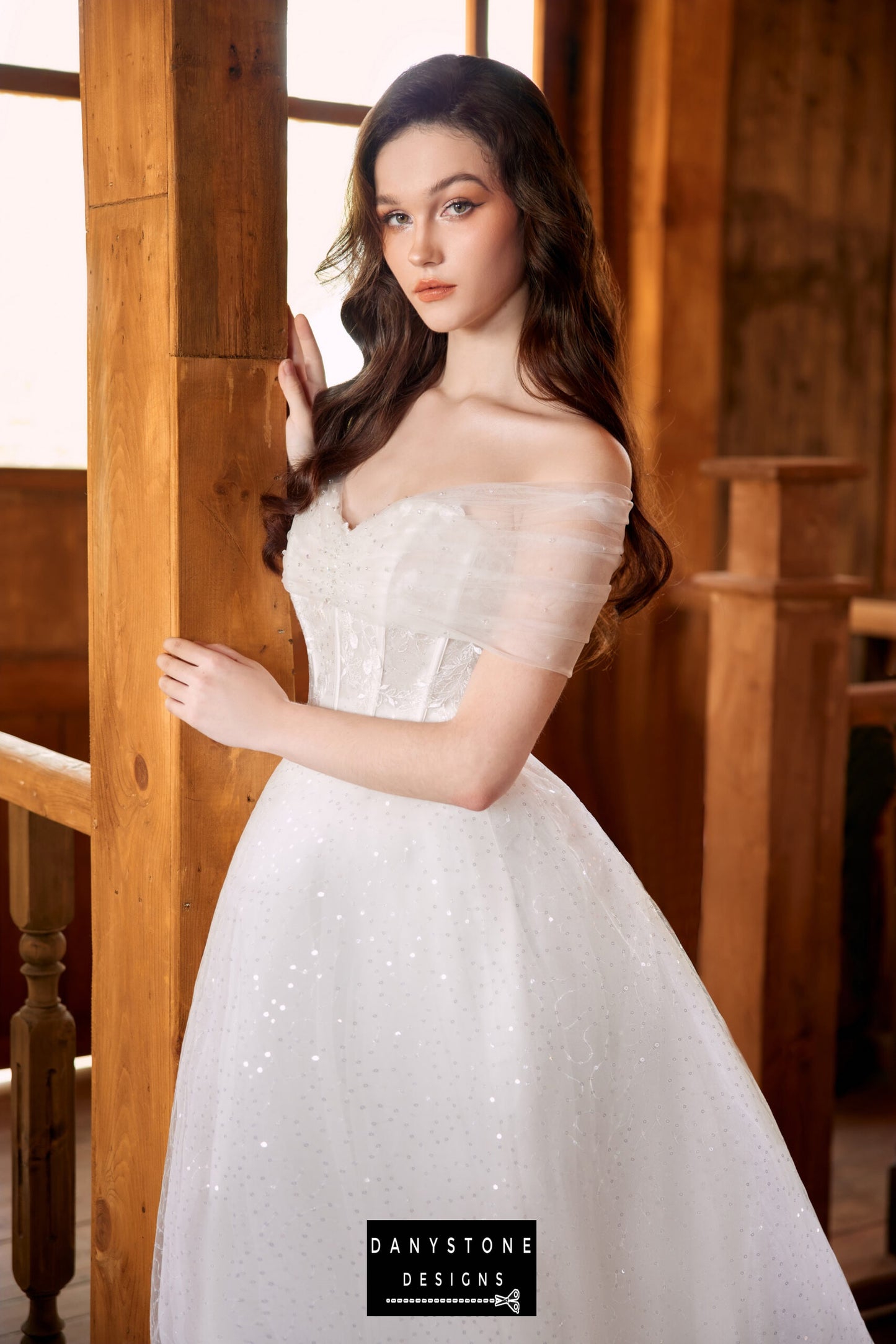 Bride posing against a wooden pillar in a strapless wedding dress with lace and mesh chiffon overlay.