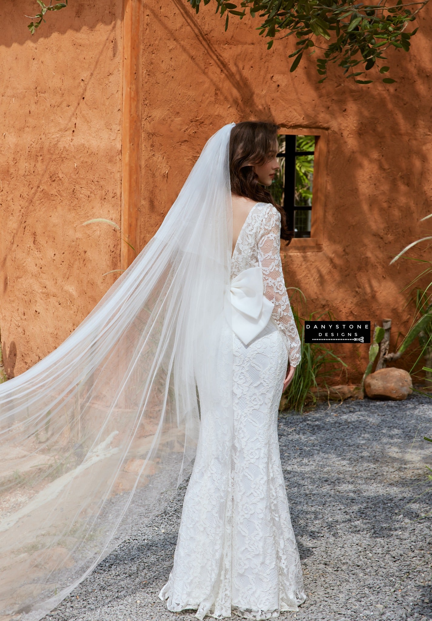 Elegant full lace fishtail wedding dress with boat neck and bow back by Danystone Designs - back view with veil.