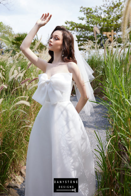 Strapless wedding dress with a bow detail, highlighting sleek silhouette - Danystone Designs.