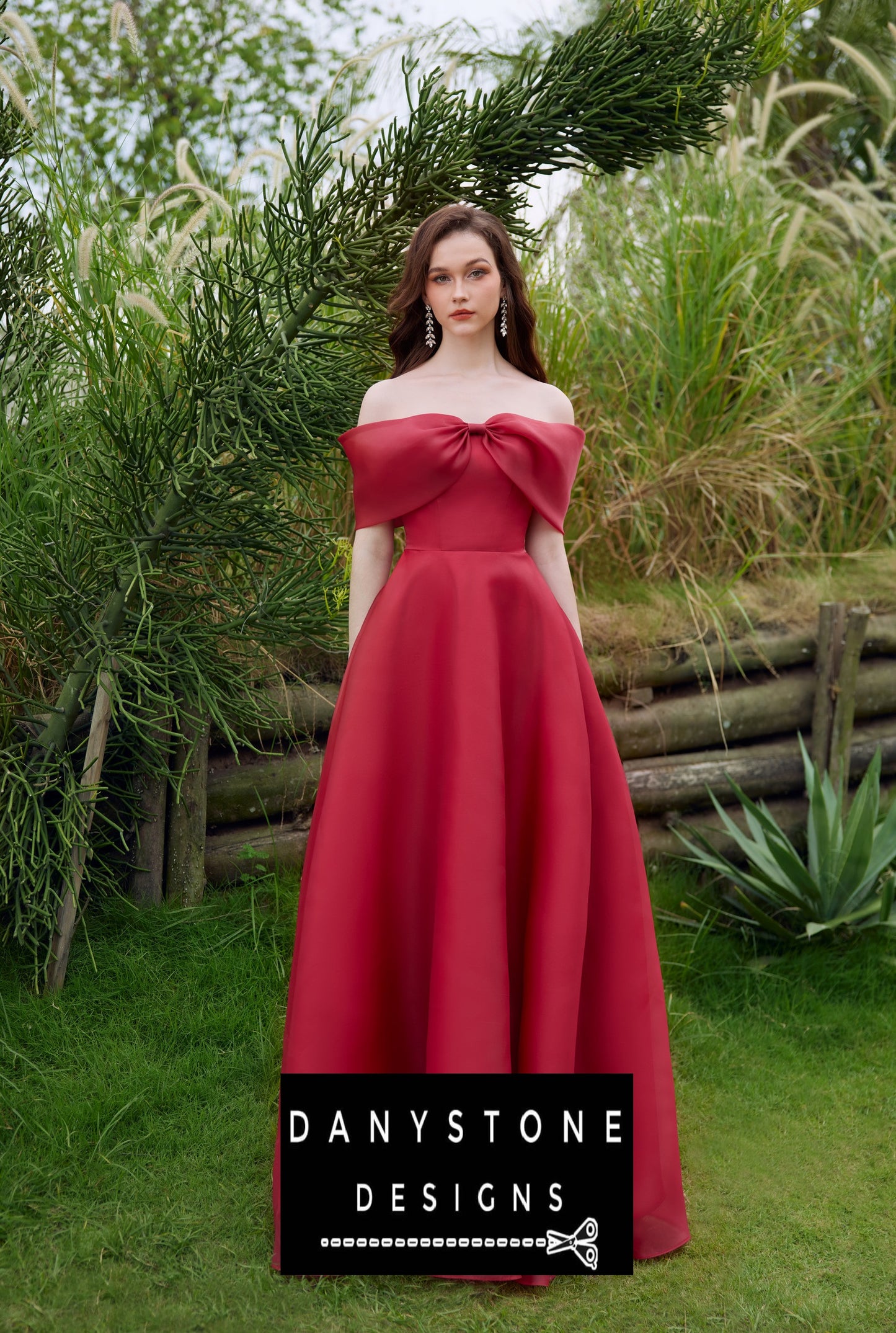 Woman in a red silk chiffon dress with an off-shoulder design and bow