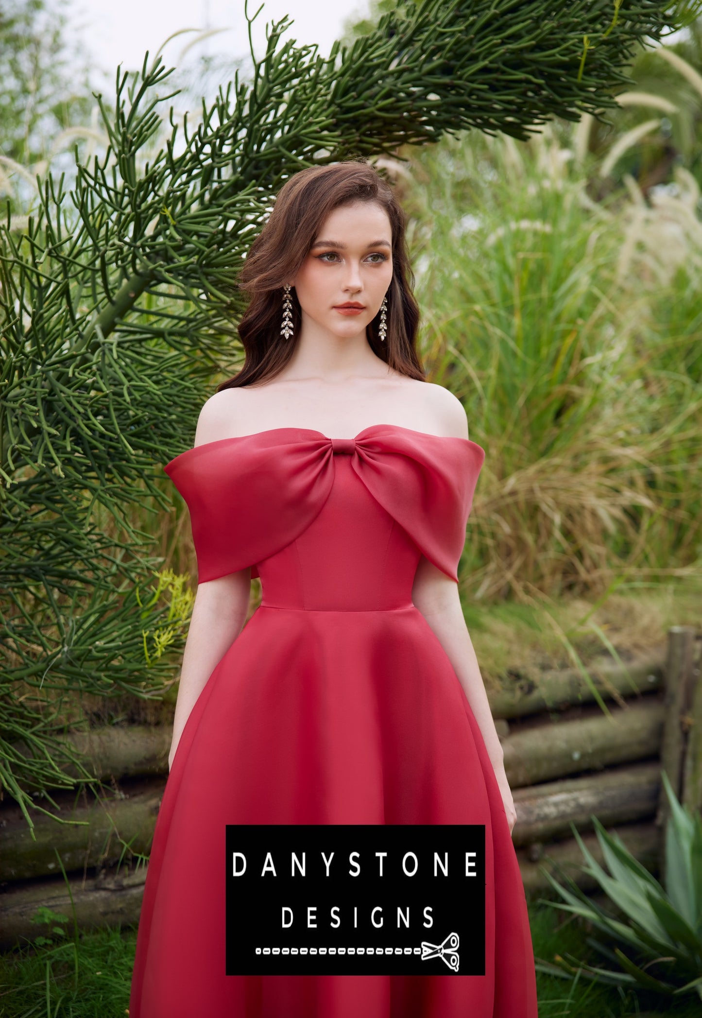 Red off-shoulder silk chiffon dress with chest bow modeled in a garden