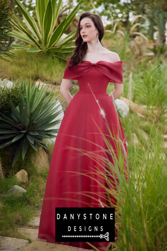 Model wearing an elegant red off-shoulder silk chiffon dress with a bow