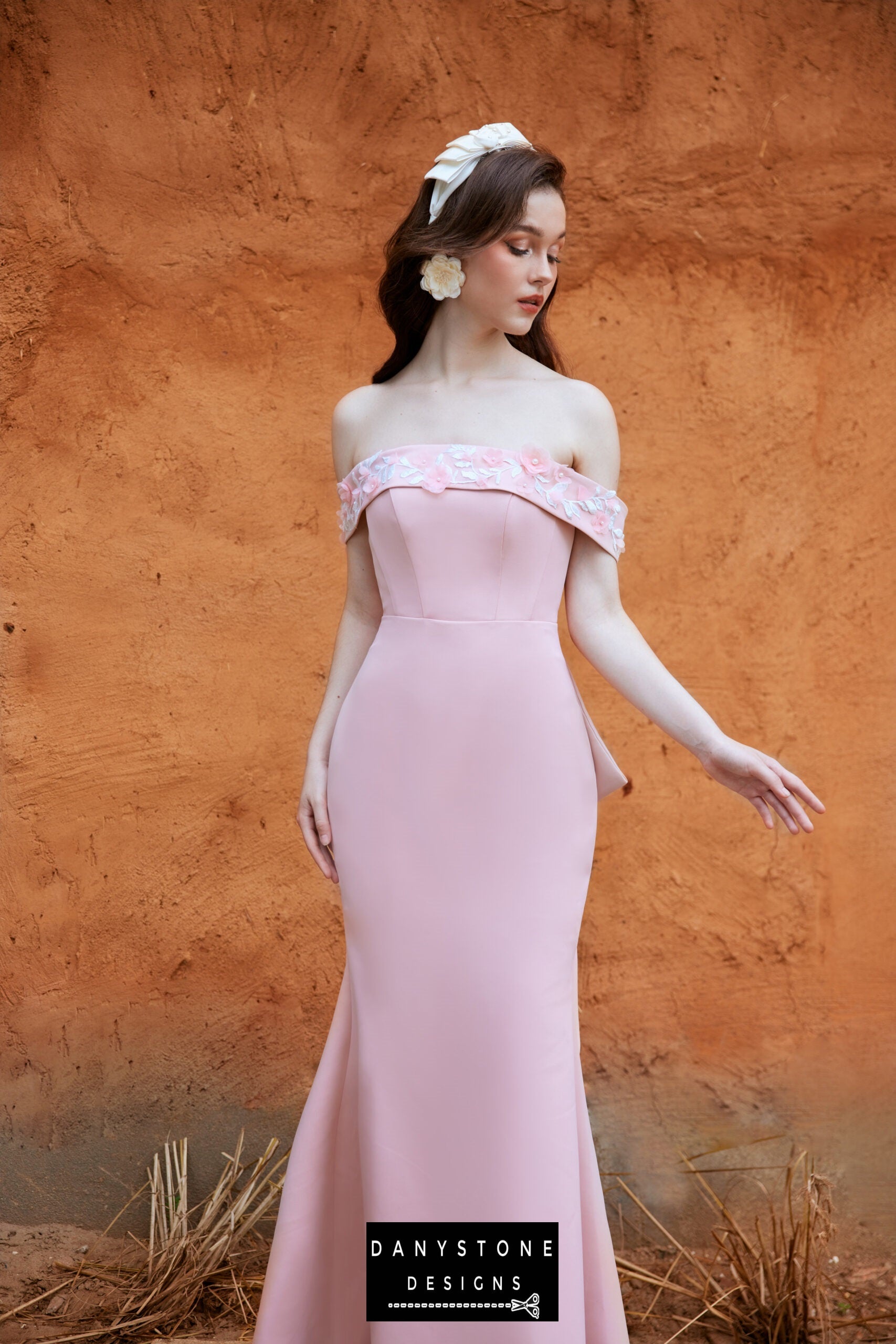 Woman in a pink satin fishtail dress with an off-shoulder design and floral details