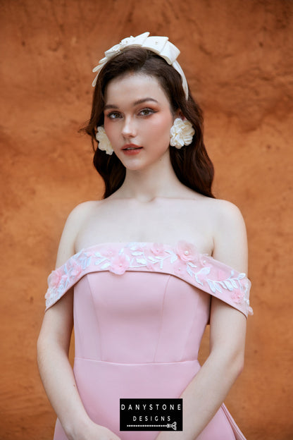 Pink off-shoulder satin fishtail dress with embossed flowers modeled outdoors