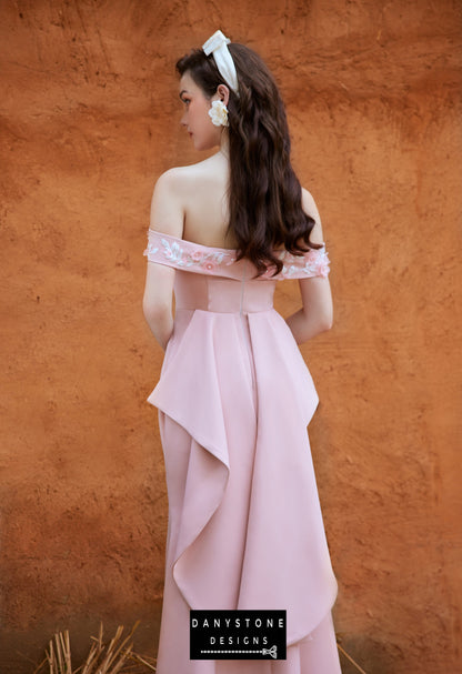 Woman in a garden wearing a pink off-shoulder satin fishtail dress with embossed flowers