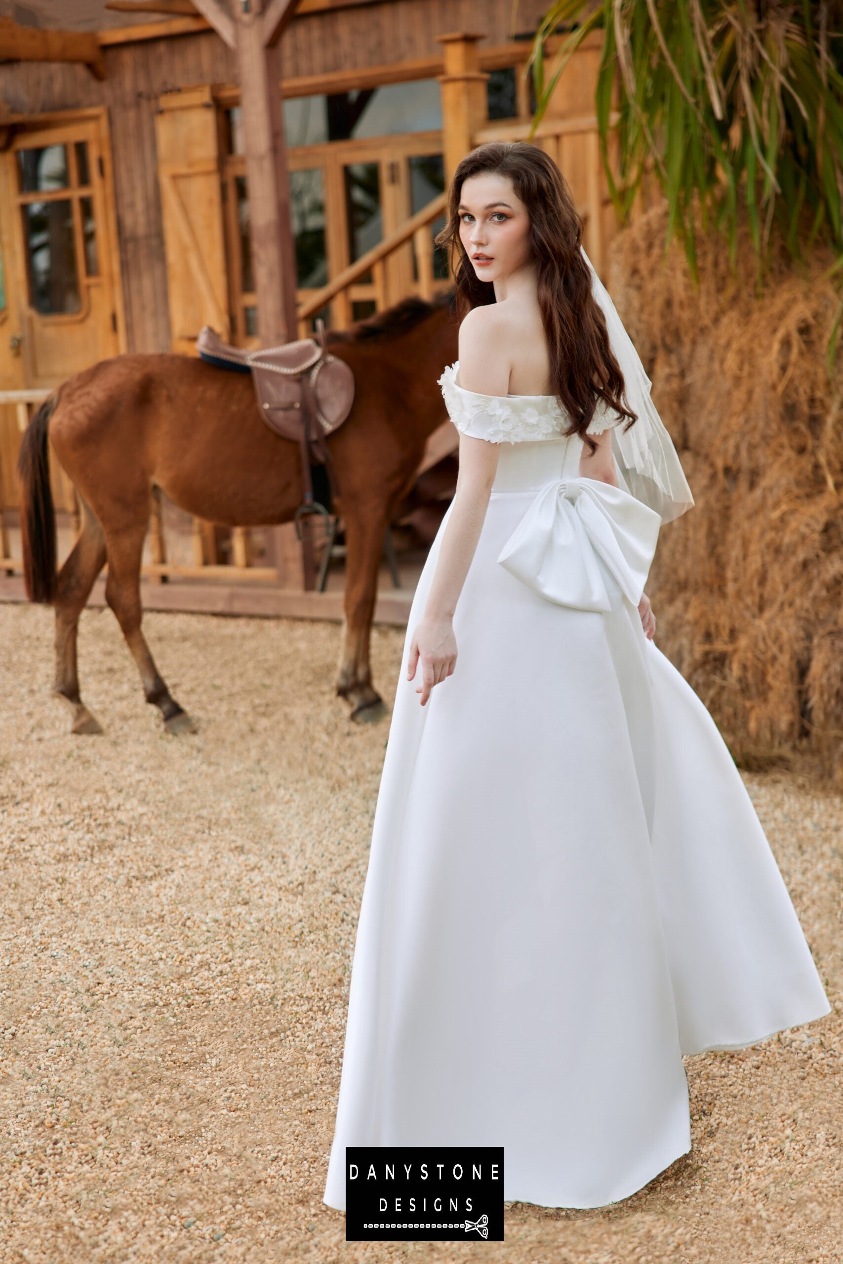 Back view of the satin wedding dress showcasing the bow detail and floral accents - Danystone Designs.