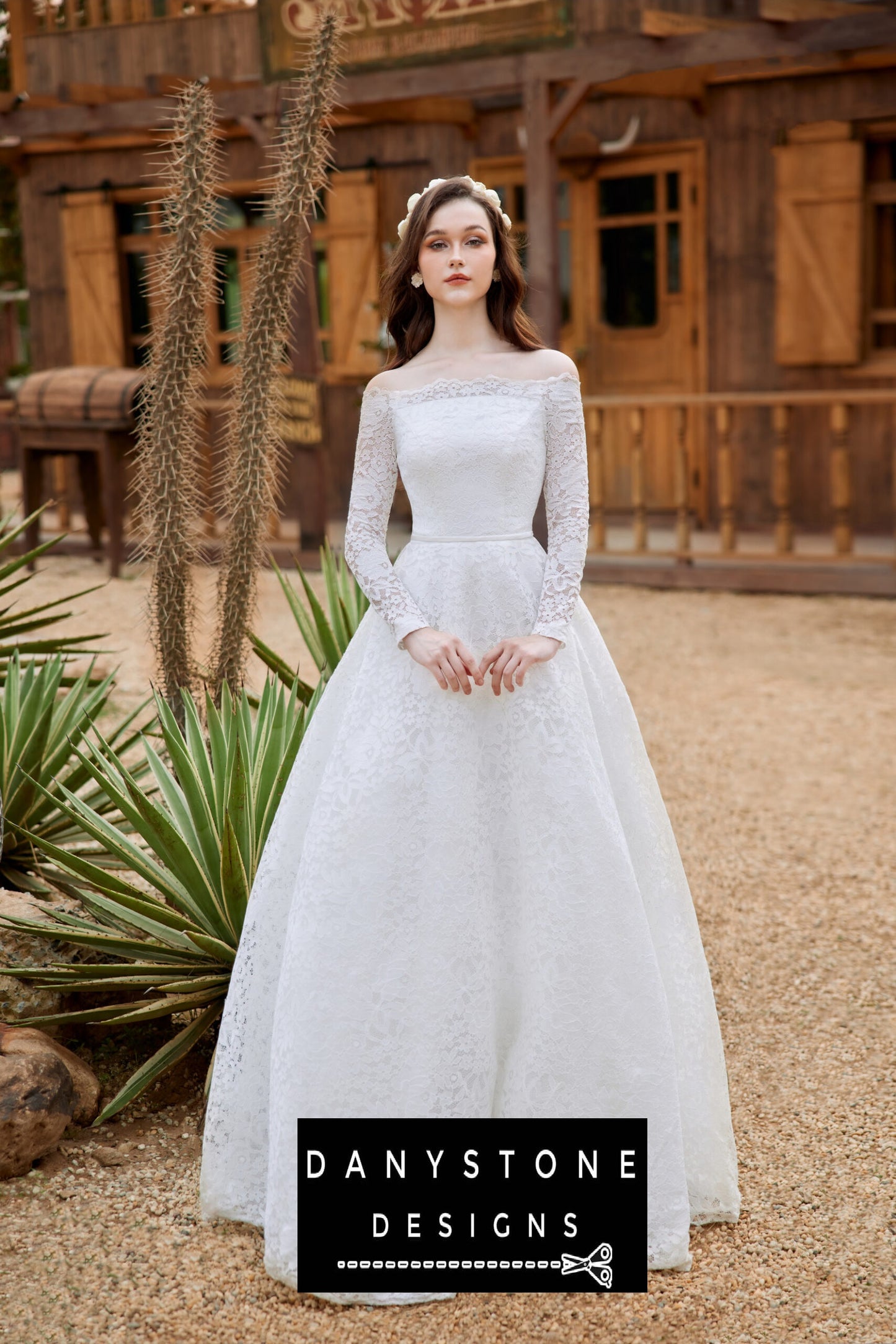 Bride standing in front of a rustic building, wearing a lace wedding dress with puffed shoulders and a full-length skirt.