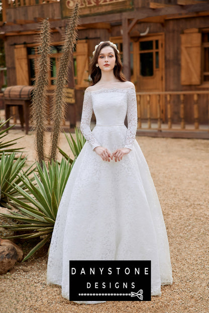 Bride standing in front of a rustic building, wearing a lace wedding dress with puffed shoulders and a full-length skirt.