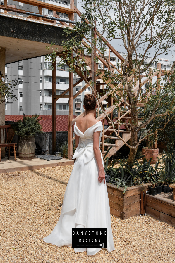 Timeless Silk Chiffon Wedding Gown - Model posing outdoors, highlighting the off-the-shoulder neckline and the enchanting flow of the silk chiffon fabric.