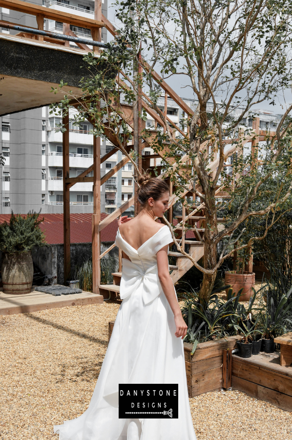 Timeless Silk Chiffon Wedding Gown - Model posing outdoors, highlighting the off-the-shoulder neckline and the enchanting flow of the silk chiffon fabric.