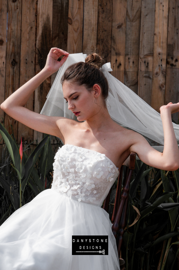 Model showcasing the strapless design and intricate 3D flower appliqué details of the mini dress.