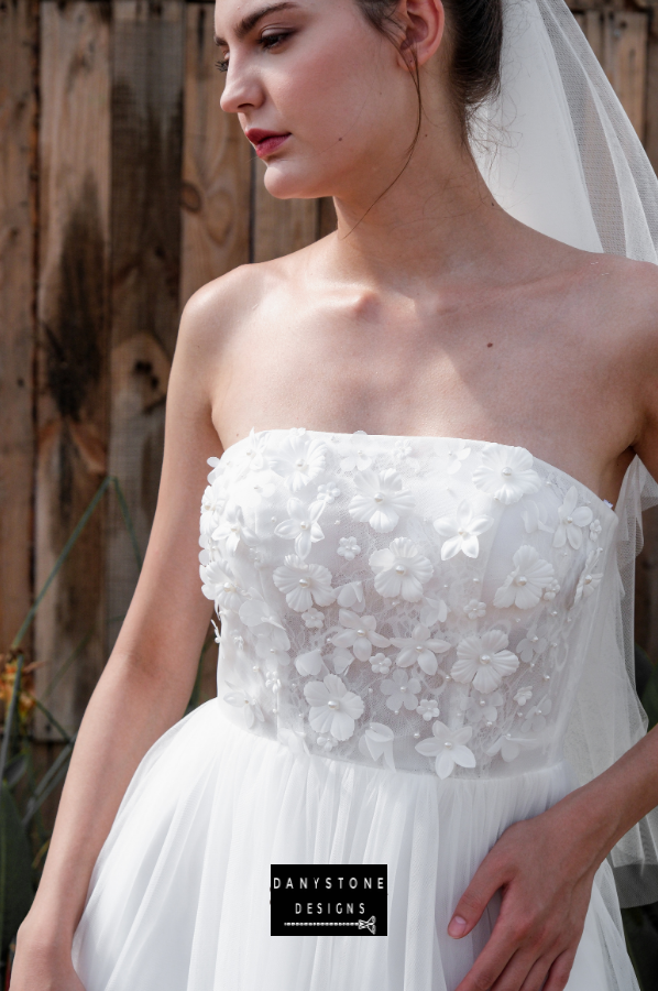 A close-up view showing the detailed 3D flower appliqué and strapless neckline of the mini dress.