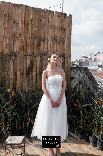 Model posing in an outdoor setting wearing the mini dress with 3D flowers and mesh parts.