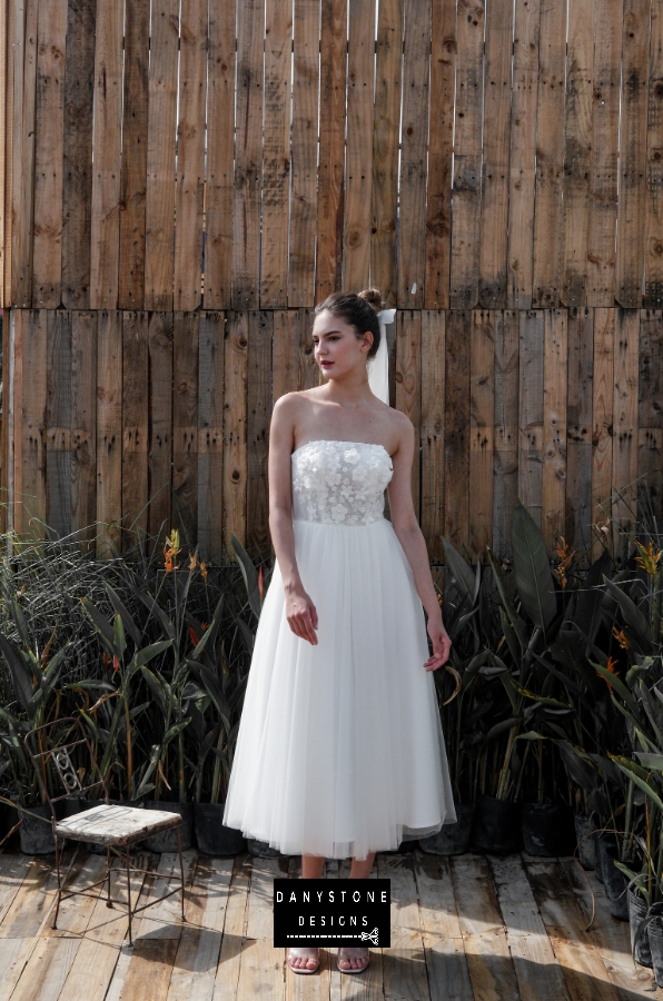 Model sitting and showcasing the elegance of the mini dress with 3D flower appliqué and mesh details.