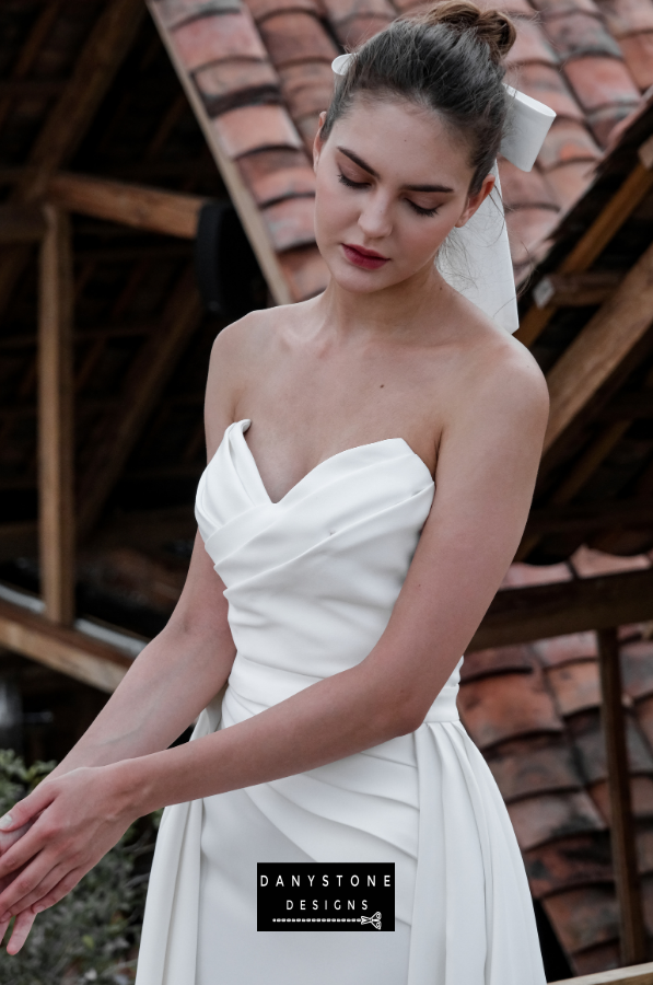 Graceful Pleated Strapless Gown - Back view of the model with the flowing skirt and elegant pleats, perfect for a timeless bridal look.