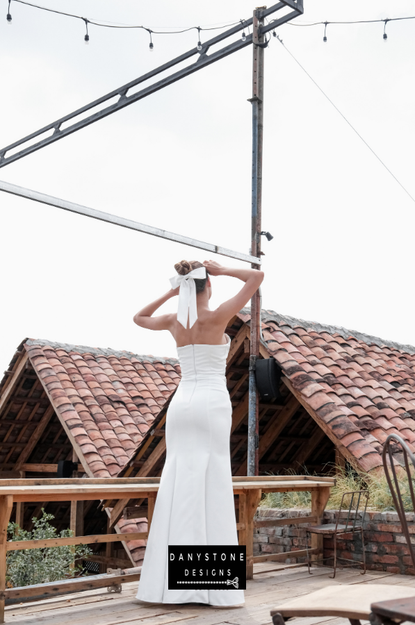 Model showcasing the back view of the elegant pleated strapless gown with a flowing skirt.