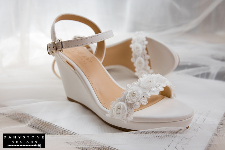 Top view of matte white leather canoe heels with white rose lace trim, highlighting the delicate floral design.