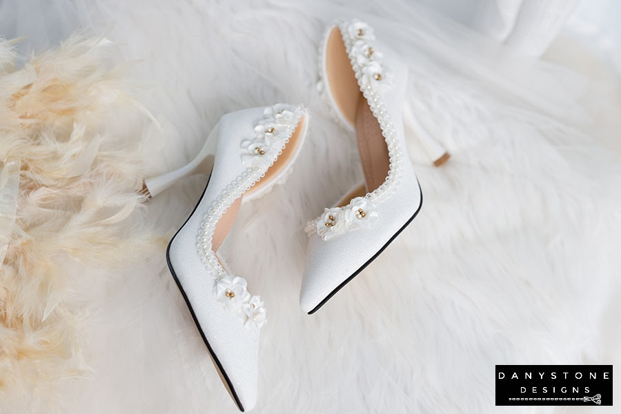 Side view of wedding shoes with open waist, showcasing pearl trim and floral accents.