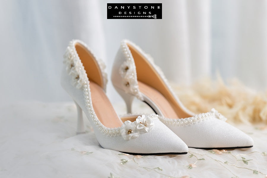 Wedding shoes with open waist, pearl trim, and floral accents, perfect for a sophisticated bridal look.