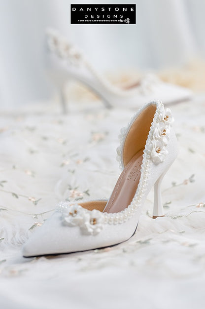 Elegant wedding shoes with open waist, pearl trim, and floral accents, featuring high heels.