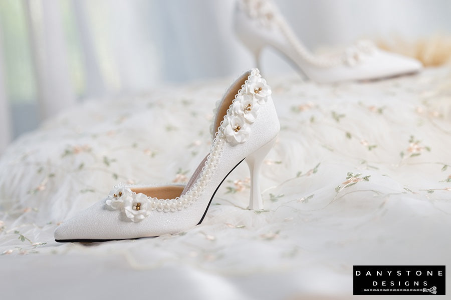 Elegant wedding shoes with open waist, pearl trim, and floral accents, featuring high heels.