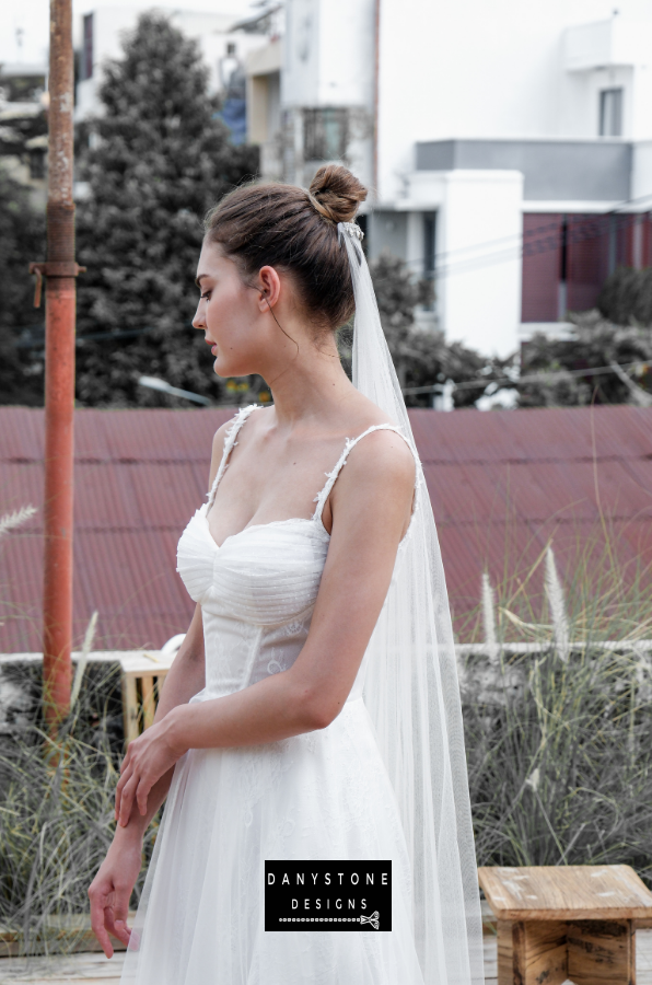 Bride in full corset lace dress with bustier bust and tulle overlay, side profile.