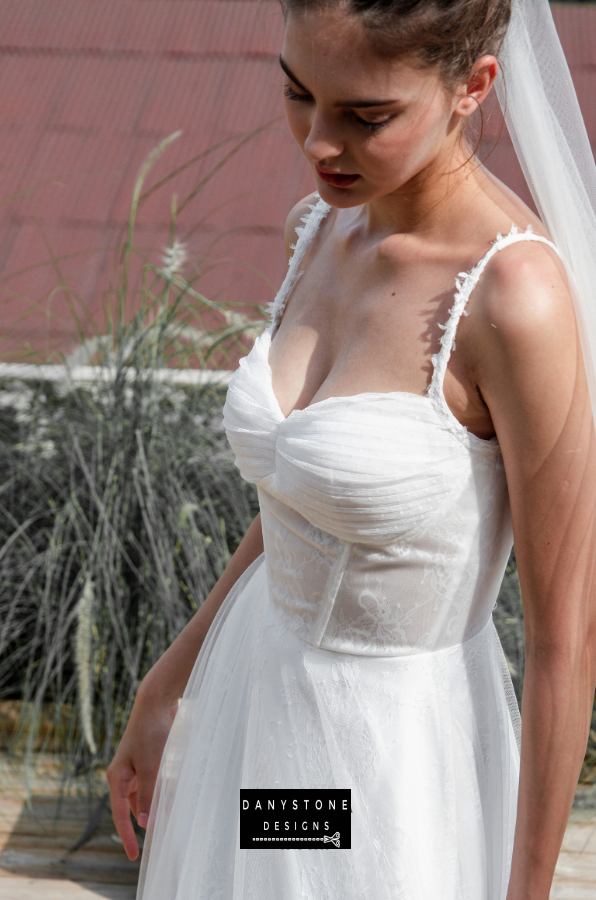 Bride in full corset lace dress with bustier bust and tulle overlay, close-up front view.