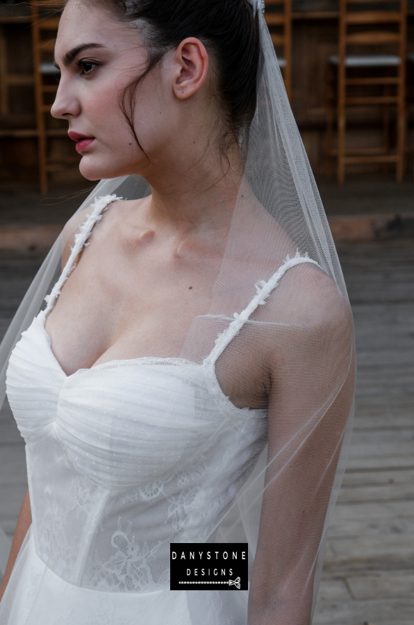 Bride in full corset lace dress with bustier bust and tulle overlay, close-up front view.