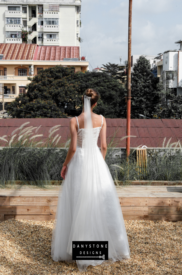 Bride in full corset lace dress with bustier bust and tulle overlay, full back view.