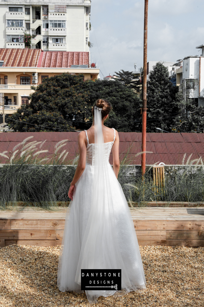 Bride in full corset lace dress with bustier bust and tulle overlay, full back view.