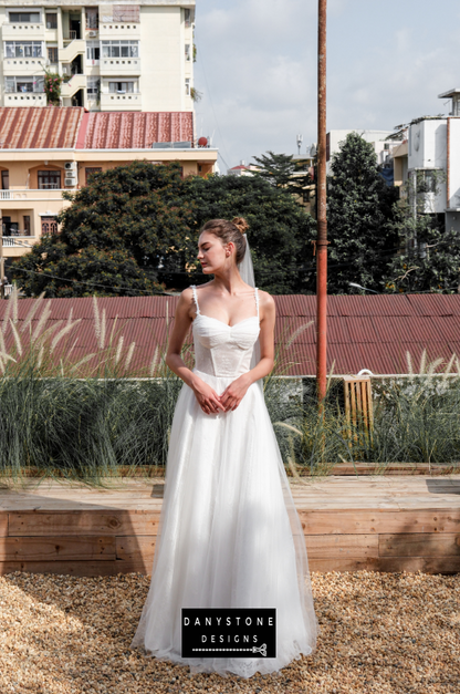 Bride in full corset lace dress with bustier bust and tulle overlay, full front view.